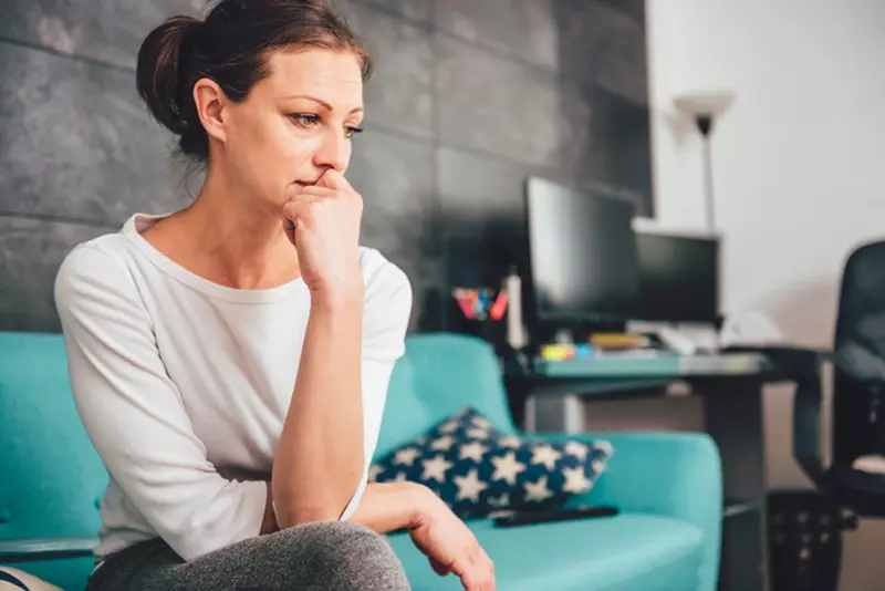 Concerned caregiver sitting on couch